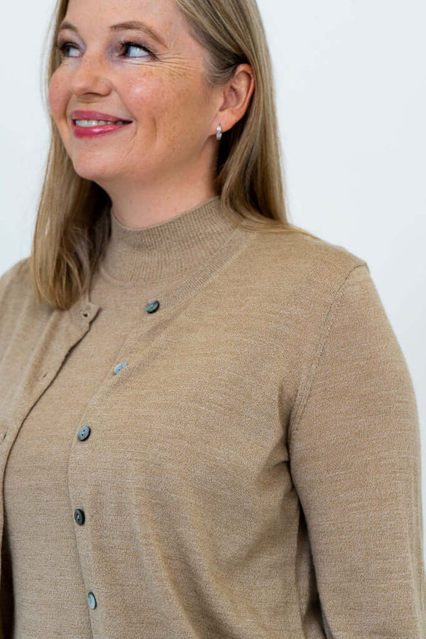Closeup of woman wearing tan Merino wool cardigan, focusing on neckline and buttons