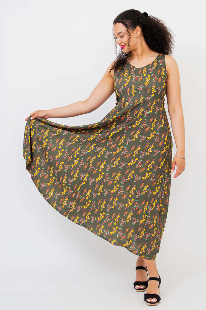 Woman displaying the flare of the Coraline floral maxi dress by holding the hem