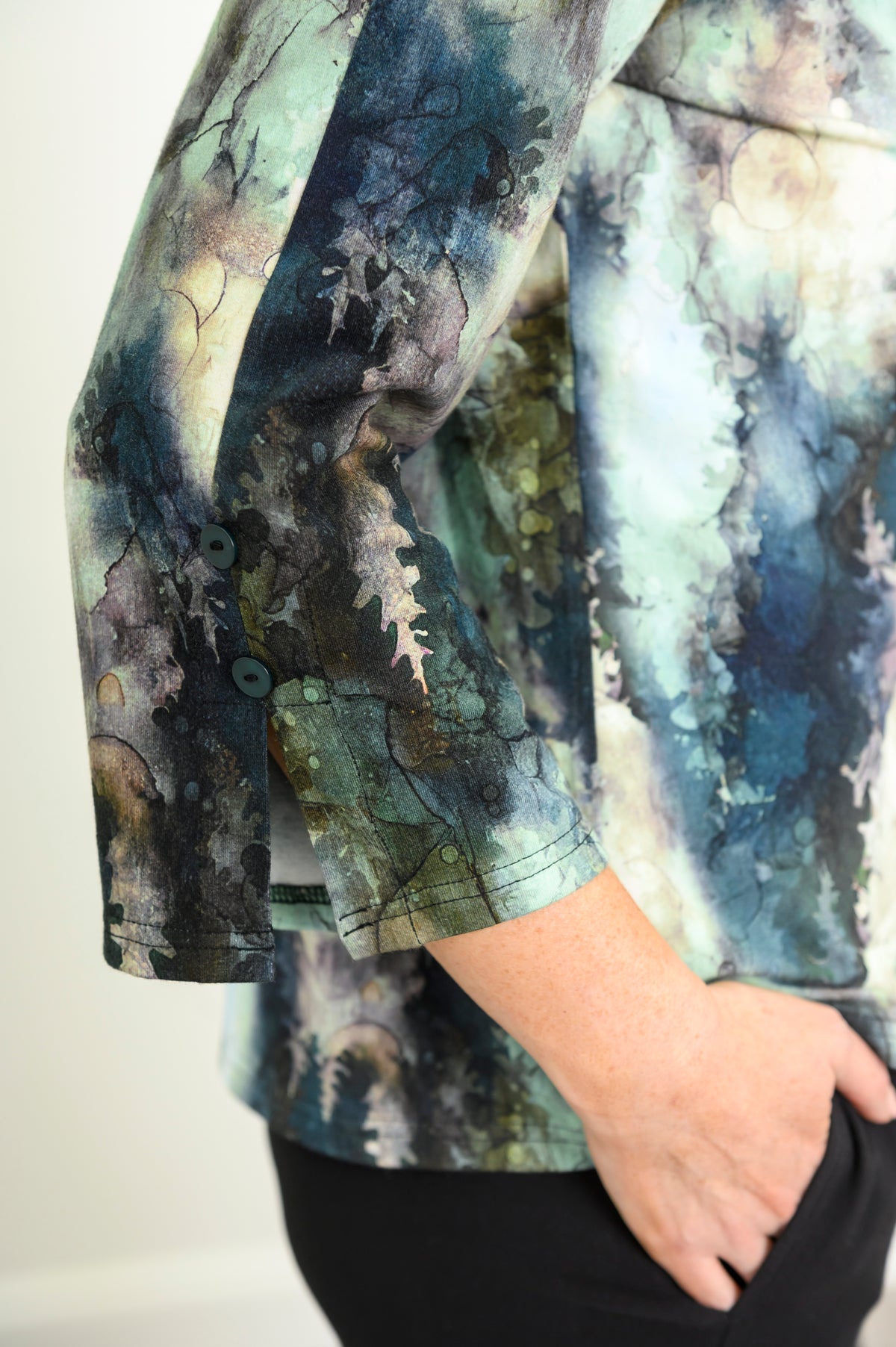 Model posing in a green patterned bamboo top, highlighting the split 3/4 bell sleeves accented with decorative buttons.