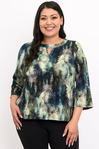 Smiling woman wearing a green forest print bamboo-cotton top with a notched neckline, front view.
