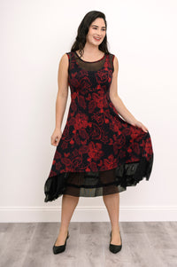 Model posing at an angle in a sleeveless red floral knit dress, highlighting the flowing, flouncy A-line skirt.