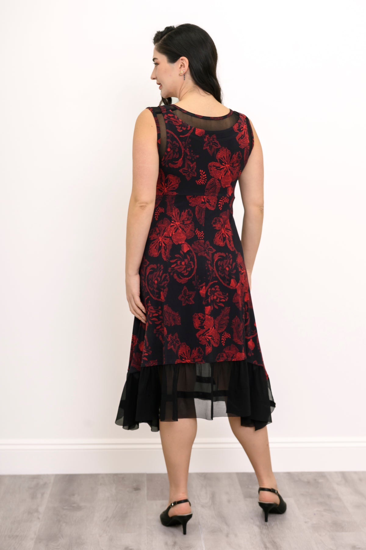 Back view of a red and black floral print bamboo dress, showcasing a fitted back bodice and flared midi hemline.