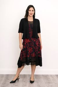Smiling woman wearing a long-sleeve black knit sweater layered over a red floral print midi dress, front view.