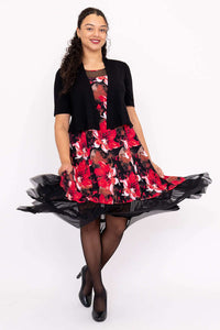 Woman twirling in floral dress with mesh hem and black cardigan