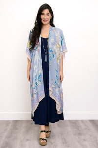Front view of woman wearing a light blue floral kimono on a navy outfit against a white background