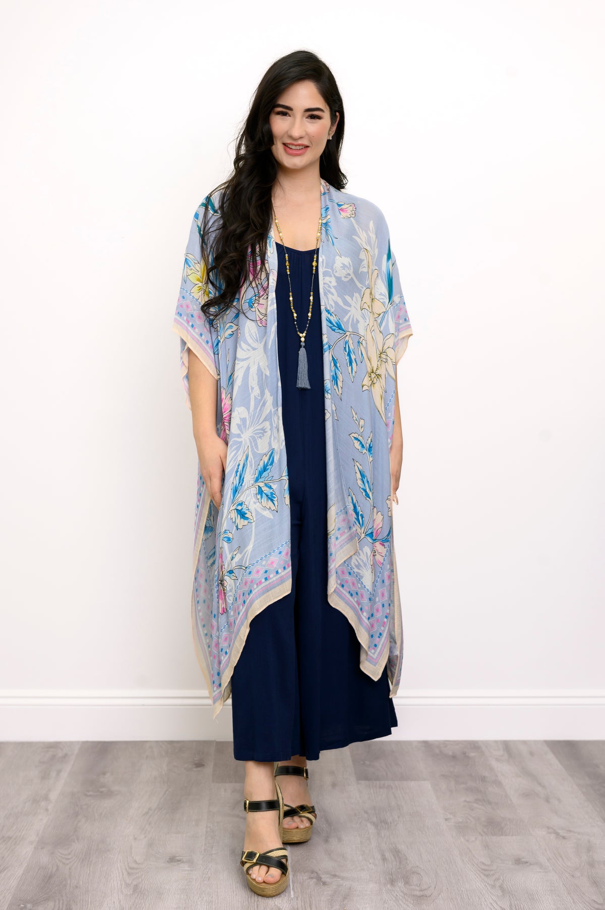 Front view of woman wearing a light blue floral kimono on a navy outfit against a white background