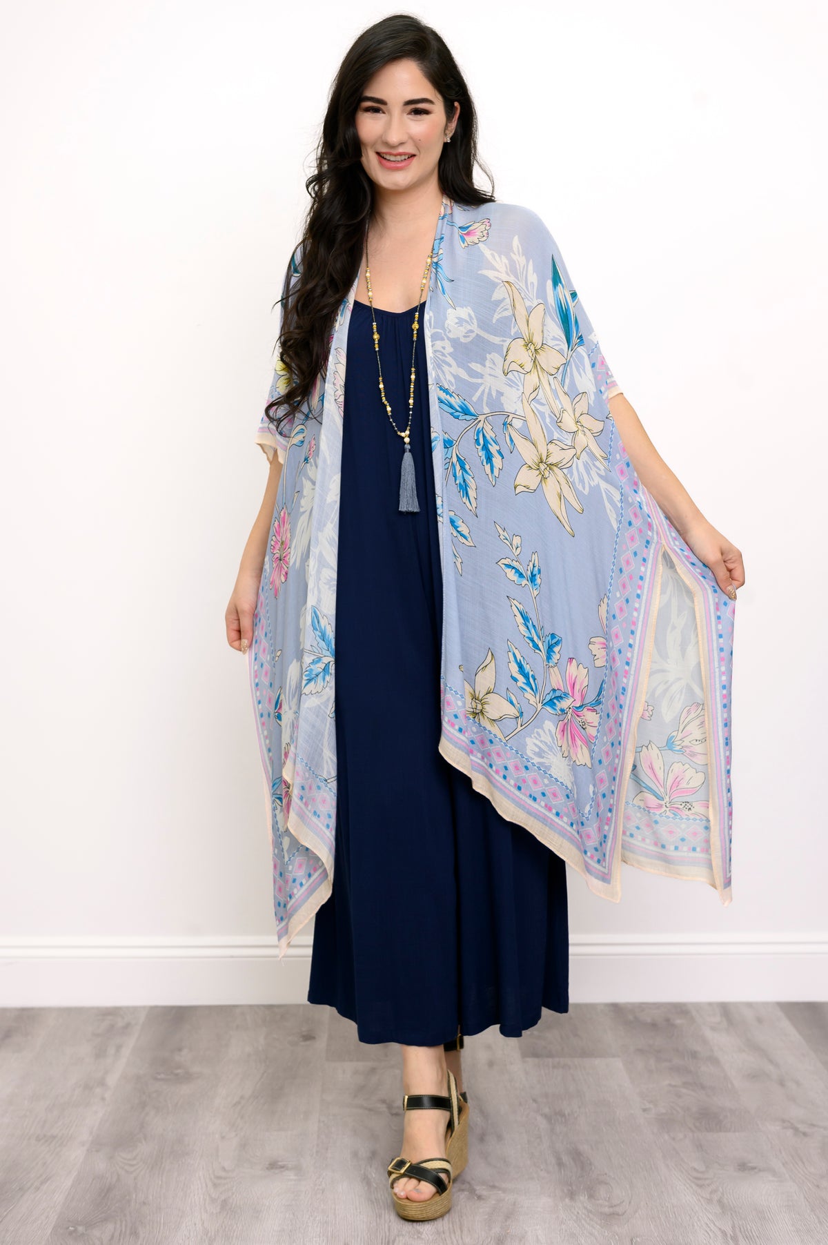 Front view of woman wearing a light blue floral kimono on a navy outfit against a white background