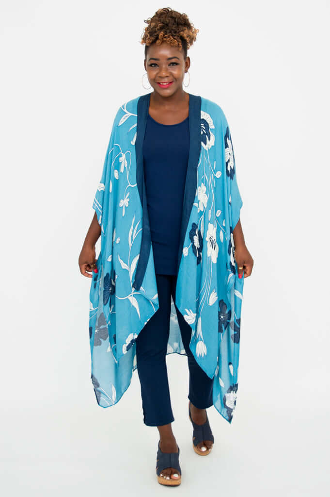 Woman holding sides of blue floral Darcy Kimono Wrap, smiling at the camera