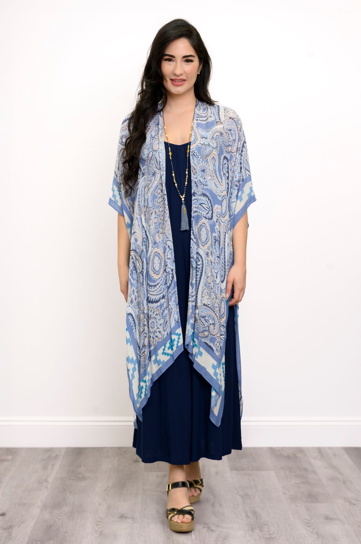 Front view of woman wearing blue paisley patterned kimono on a blue outfit against a white background 