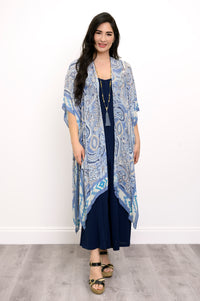 Front view of woman wearing blue paisley patterned kimono on a blue outfit against a white background 
