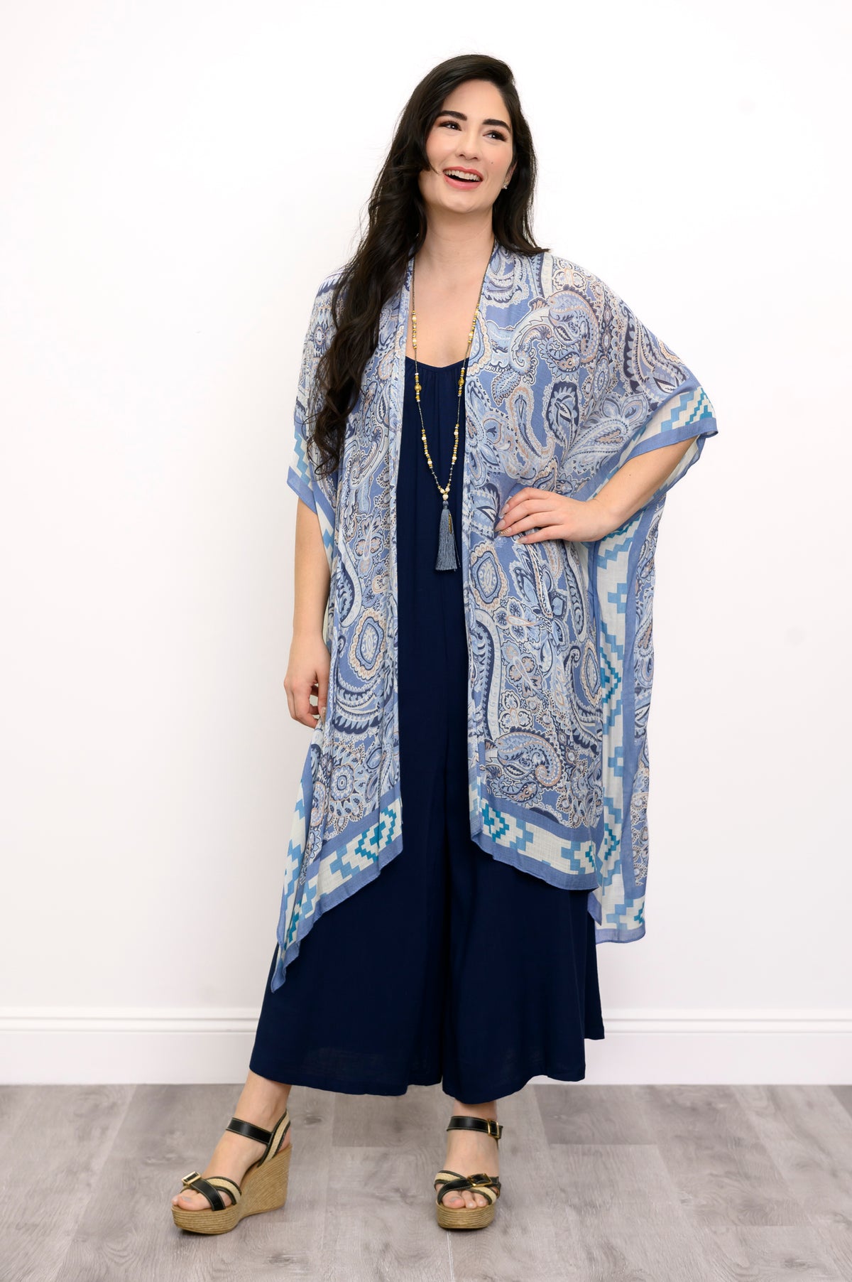 Front view of woman wearing blue paisley patterned kimono on a blue outfit against a white background 