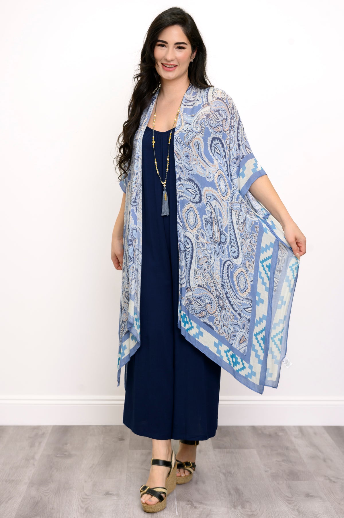 Front view of woman wearing blue paisley patterned kimono on a blue outfit against a white background 