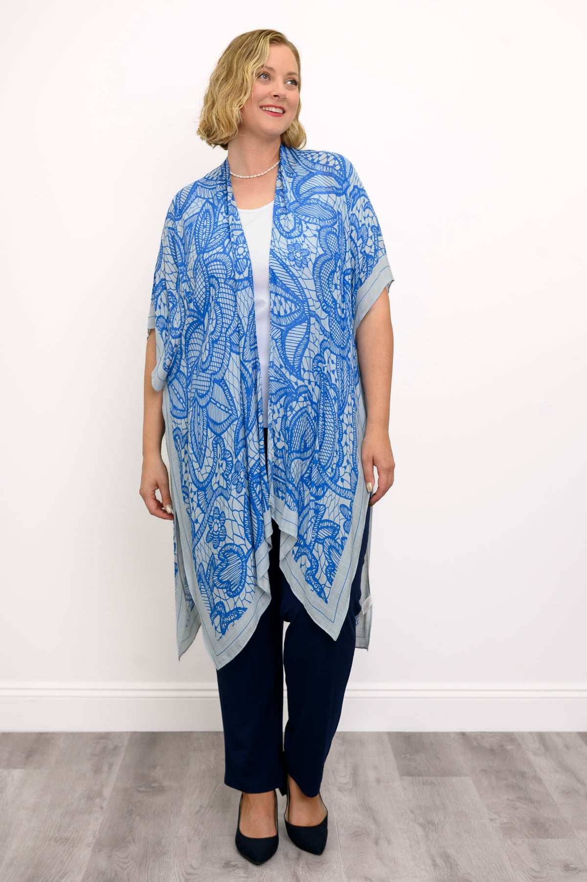 Front view of woman wearing blue lace patterned kimono on white and blue outfit against a white background 