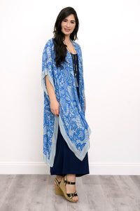 Side view of woman wearing blue lace patterned kimono on navy blue outfit against a white background 