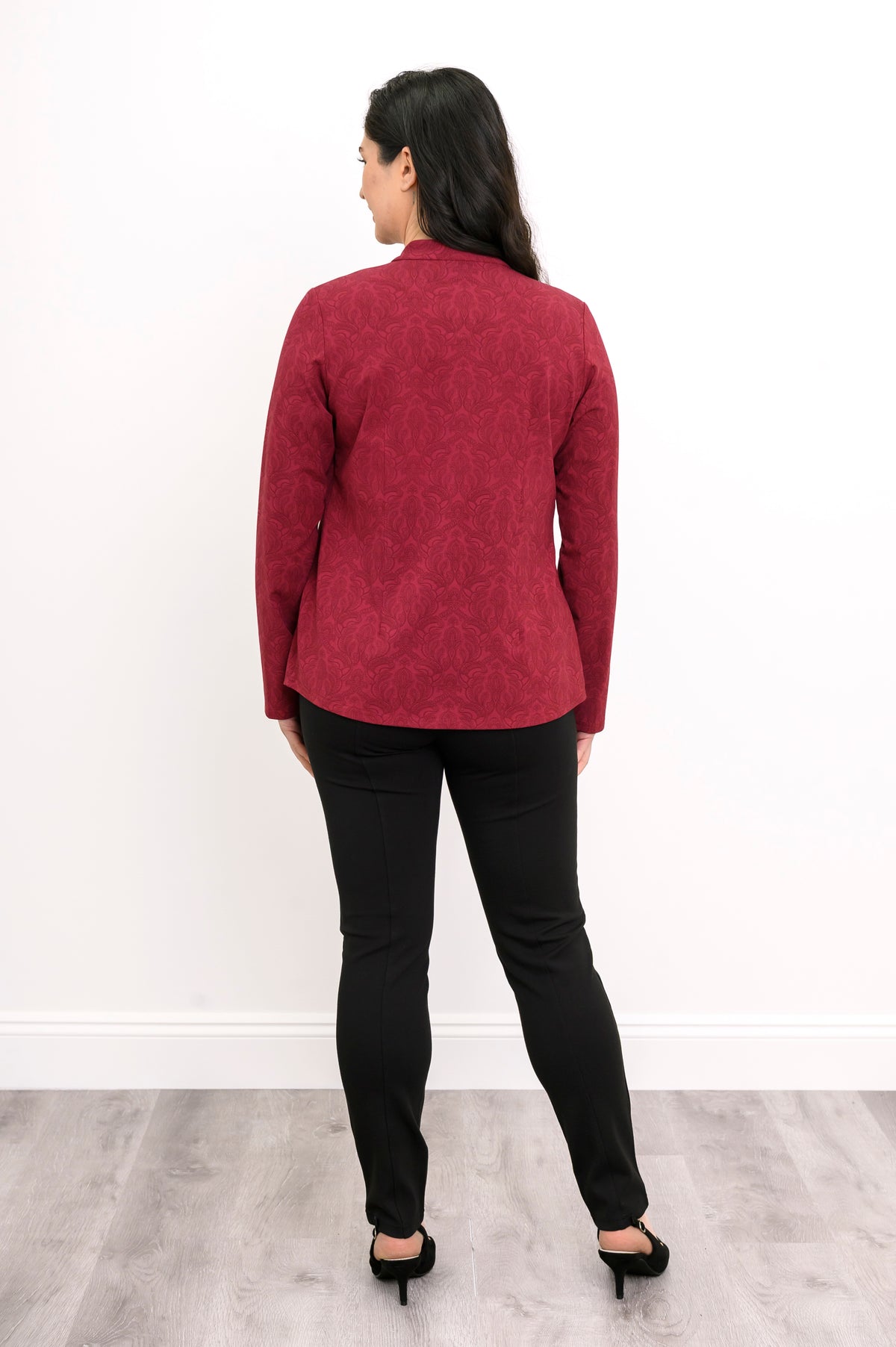 Back view of a red patterned knit top showing structured vertical princess seams and a clean, straight hem.