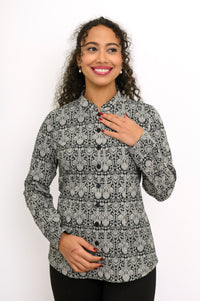 Woman gesturing while wearing a dark grey floral print button-down shirt with a mandarin collar.