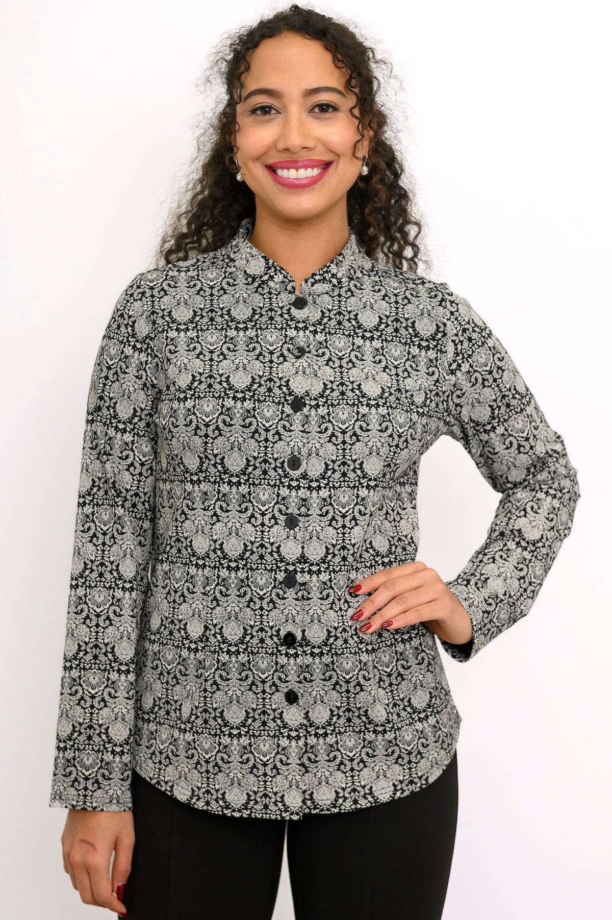 Smiling woman modeling a patterned charcoal grey long sleeve blouse with a mandarin collar and black pants