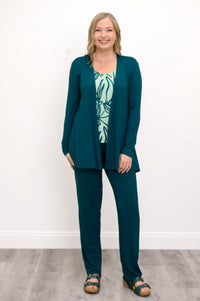 Front view, woman wearing a green sweater, green patterned top, and green pants on a white background