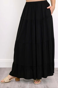 Close-up of black tiered maxi skirt with hand in pocket