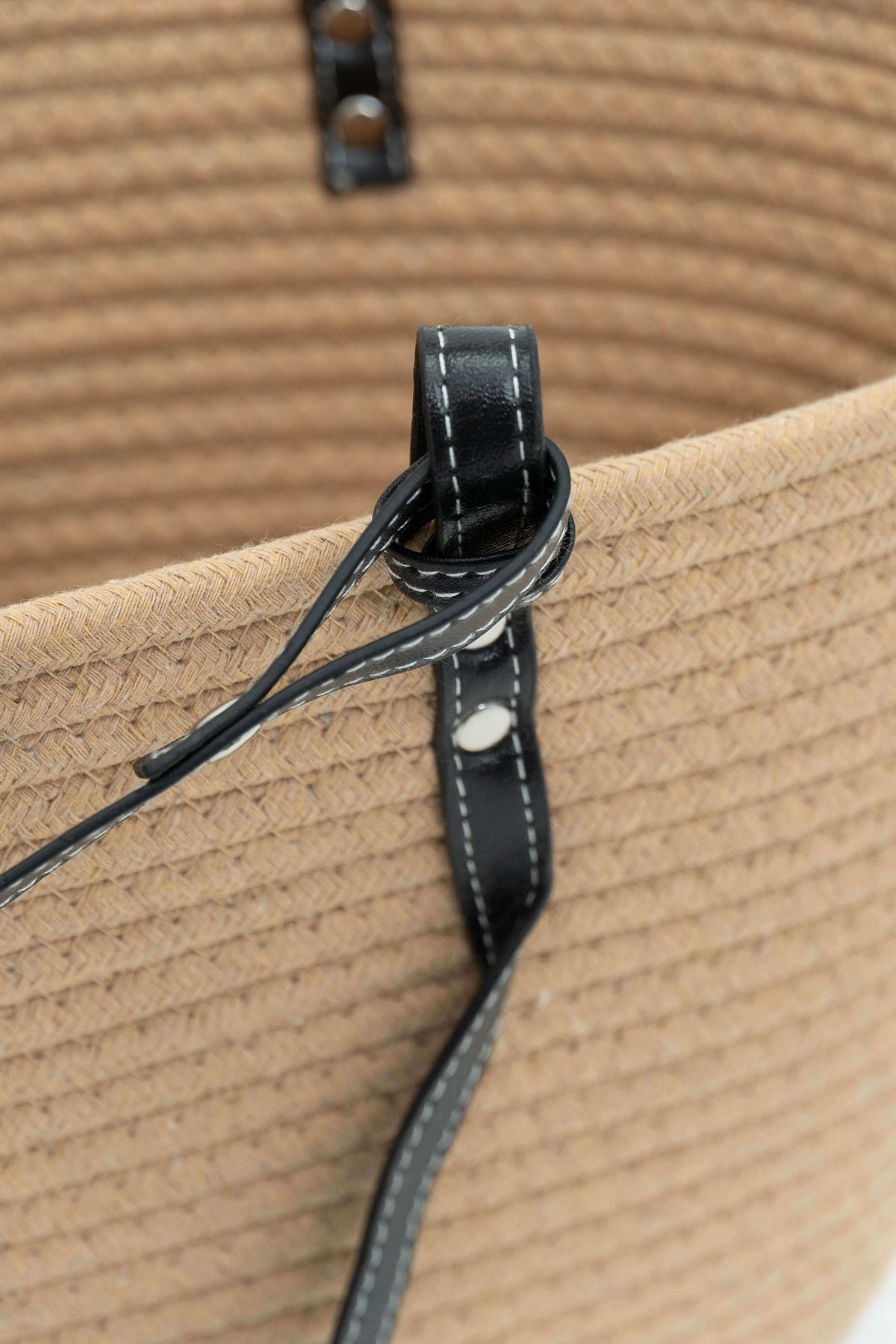 Close-up of black strap and stitching detail on tan cotton tote bag