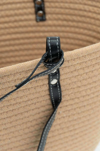 Close-up of black strap and stitching detail on tan cotton tote bag
