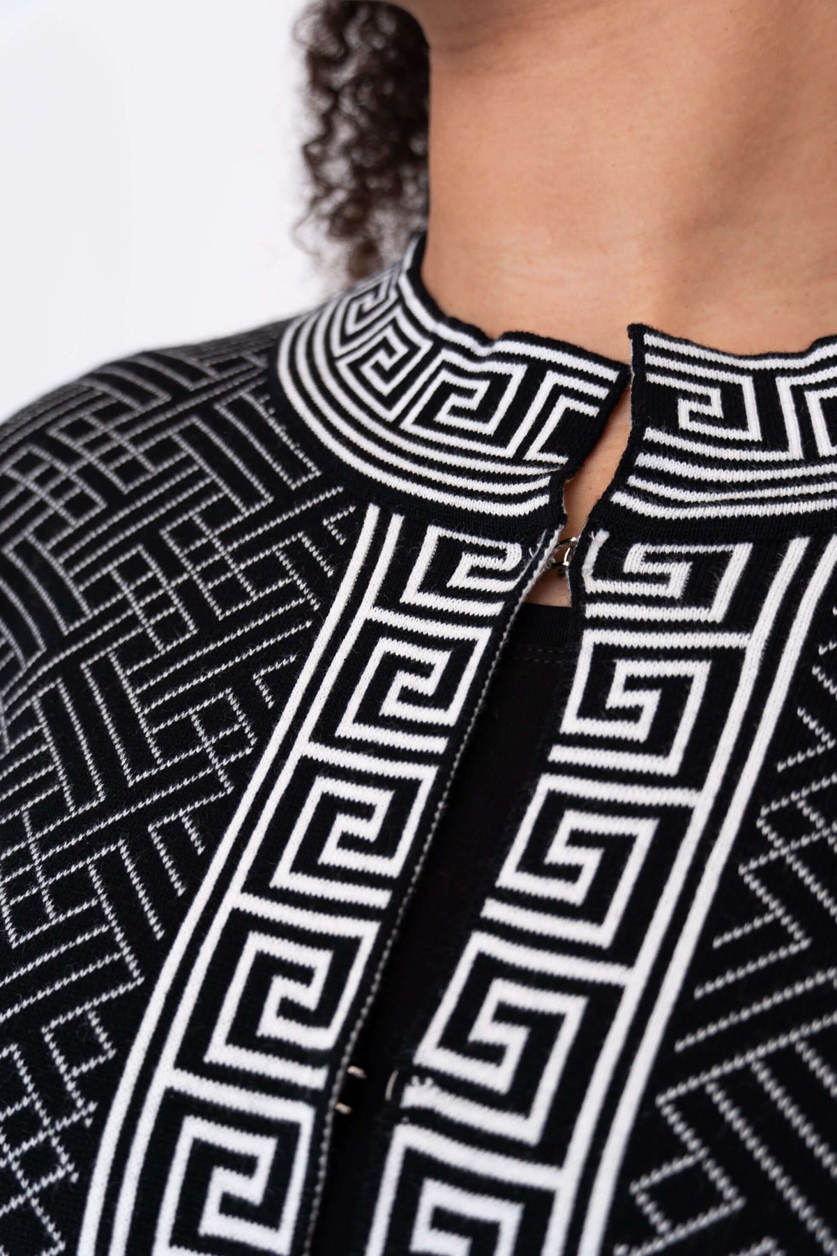 Close-up of mandarin collar and hook closure on black and white geometric knit cardigan