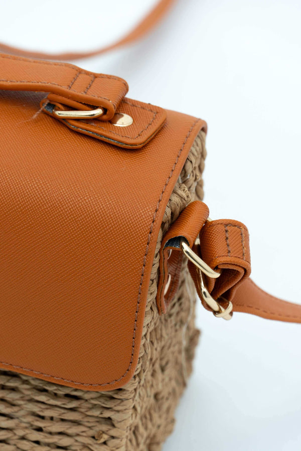 Close-up of rattan crossbody bag strap attachment and brown faux leather detail