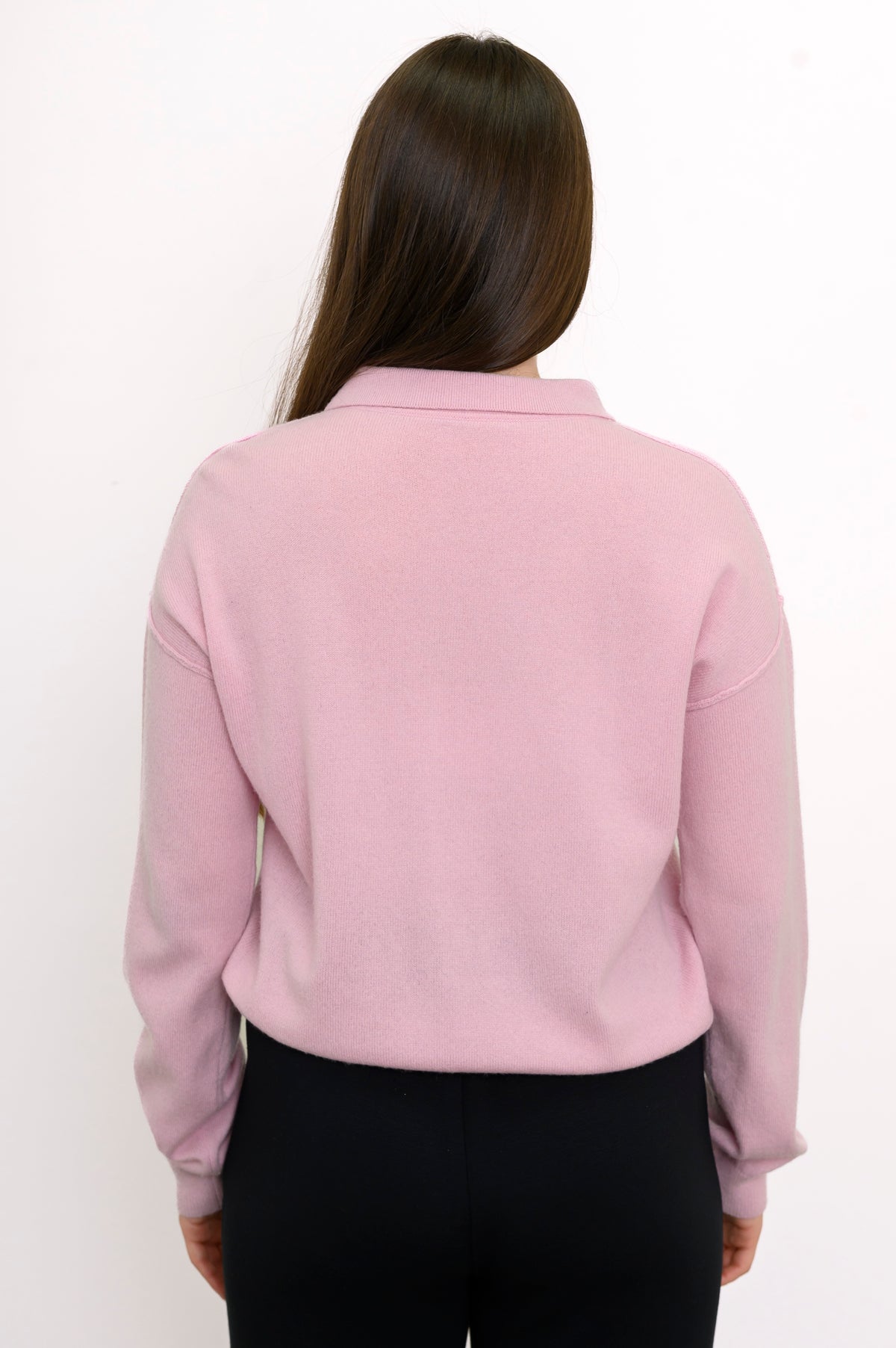 Close-up back view of woman wearing long sleeve light pink cashmere sweater with drop sleeves
