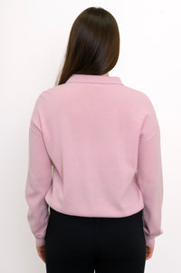 Close-up back view of woman wearing long sleeve light pink cashmere sweater with drop sleeves