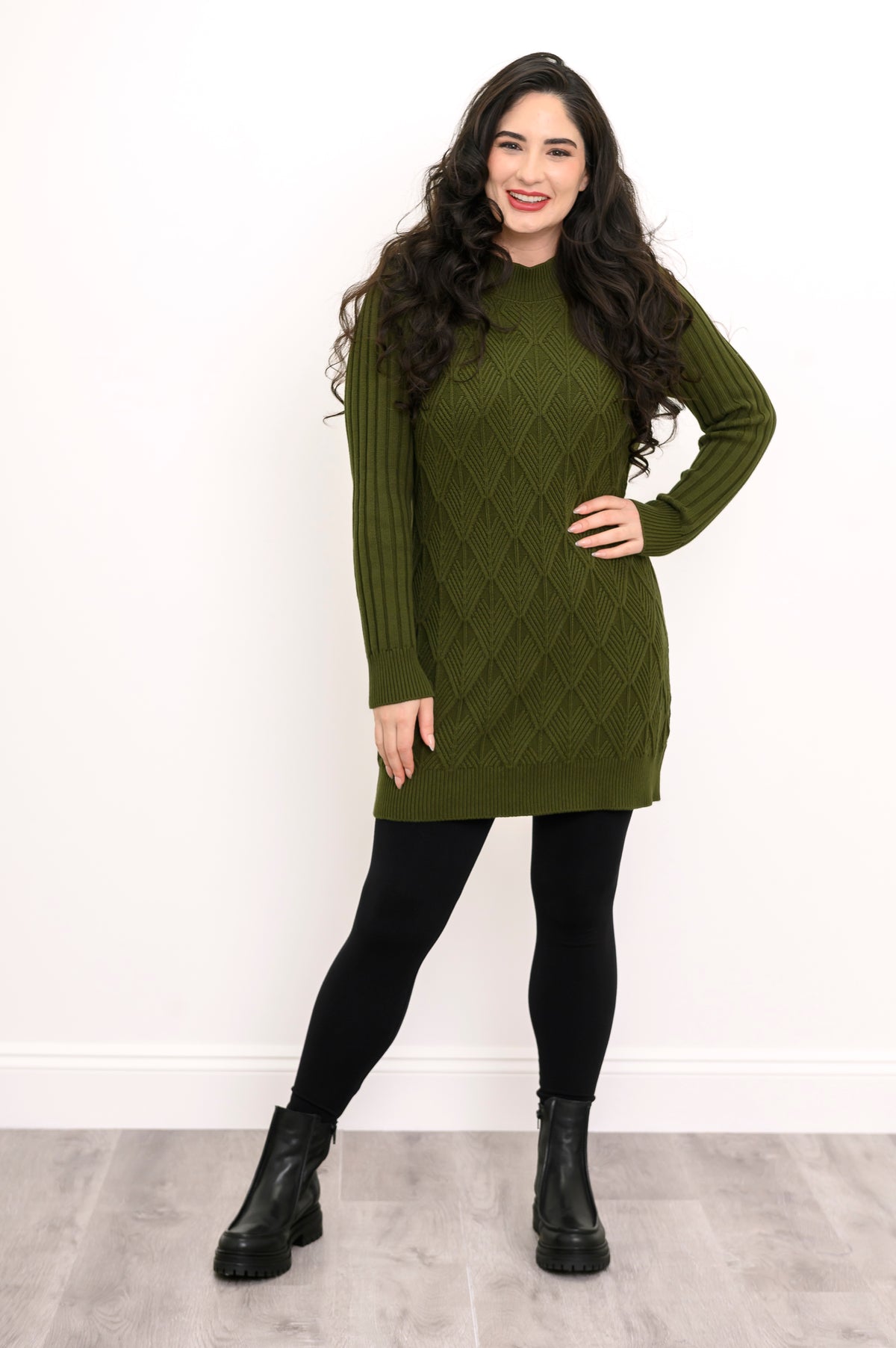 Front view of a woman modeling a breathable 100% cotton vintage green cable knit tunic for winter wear.