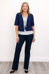 Front view, woman wearing navy blue jacket, white top, blue necklace, and blue pants against a white background