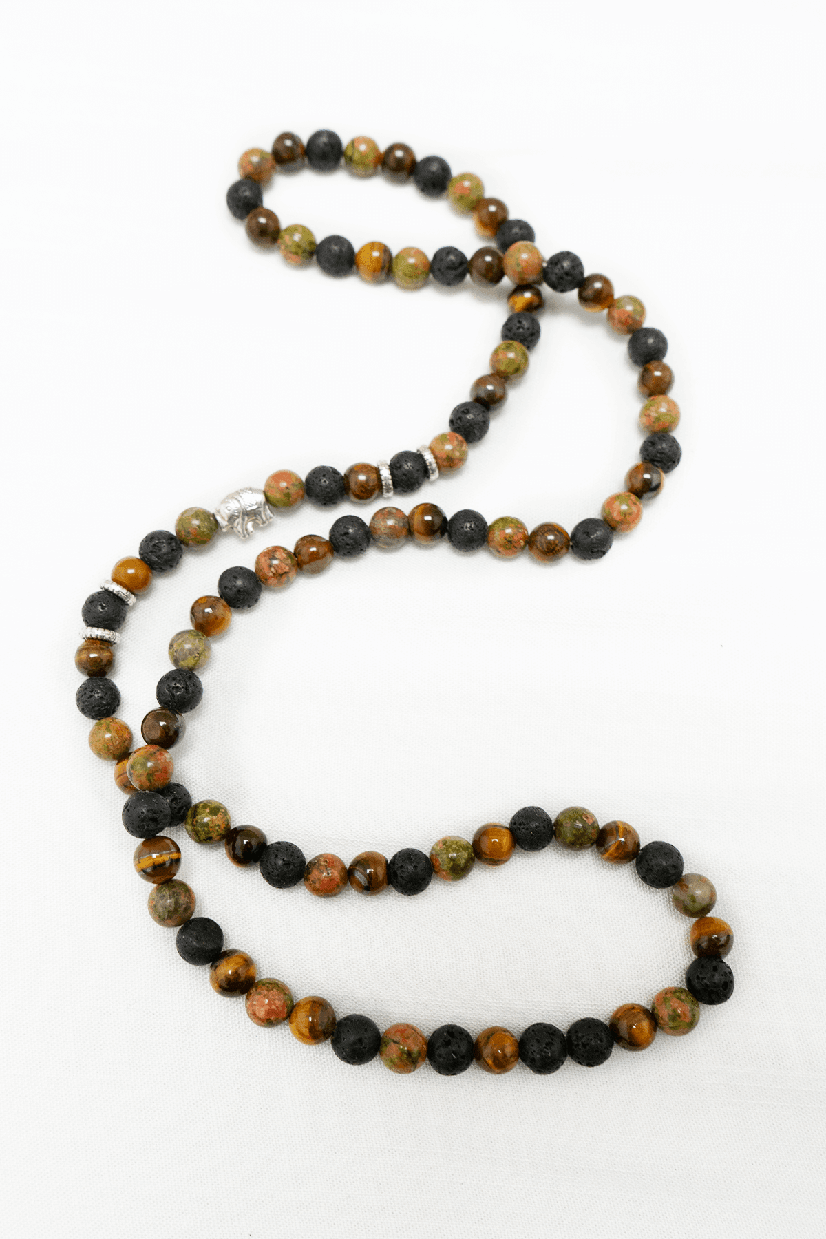 Earth-tone beaded necklace with black and brown stones, and an elephant charm on white background
