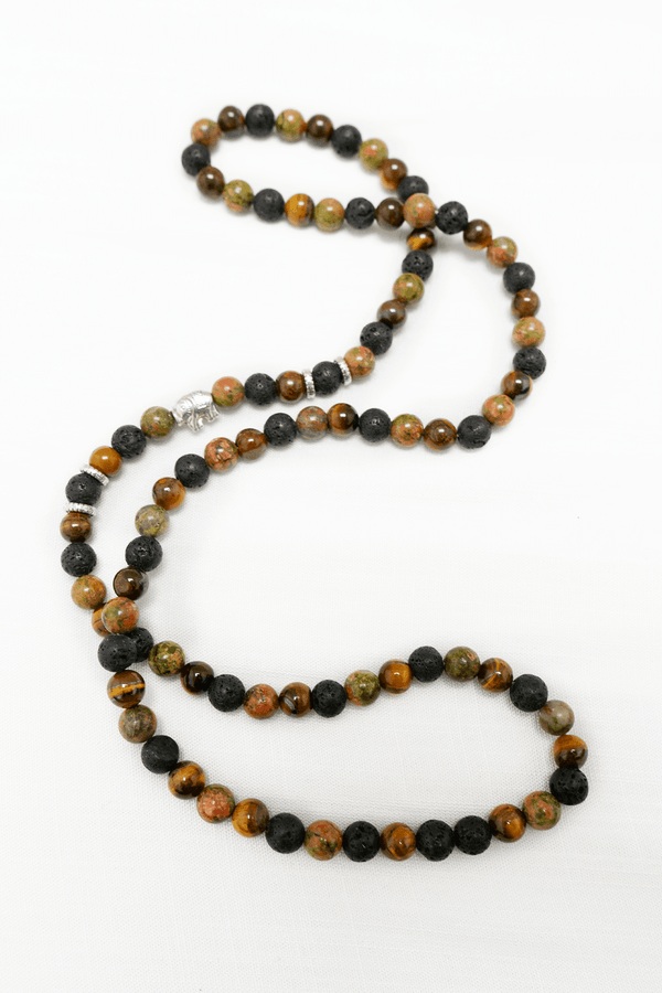 Earth-tone beaded necklace with black and brown stones, and an elephant charm on white background