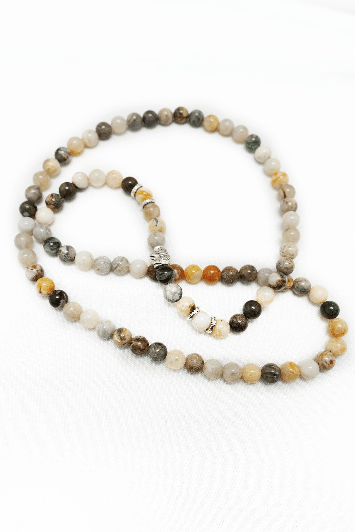 Natural stone mala necklace with mixed earth tone beads and silver accents on a white background
