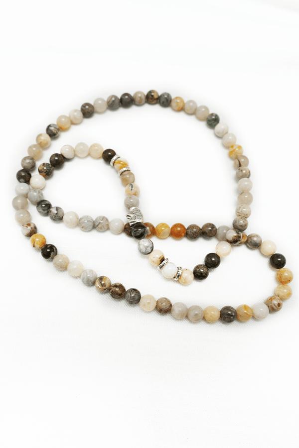 Natural stone mala necklace with mixed earth tone beads and silver accents on a white background