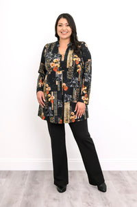 Full-length front view of a black and orange floral tunic top with a center pleat, styled with black pants.