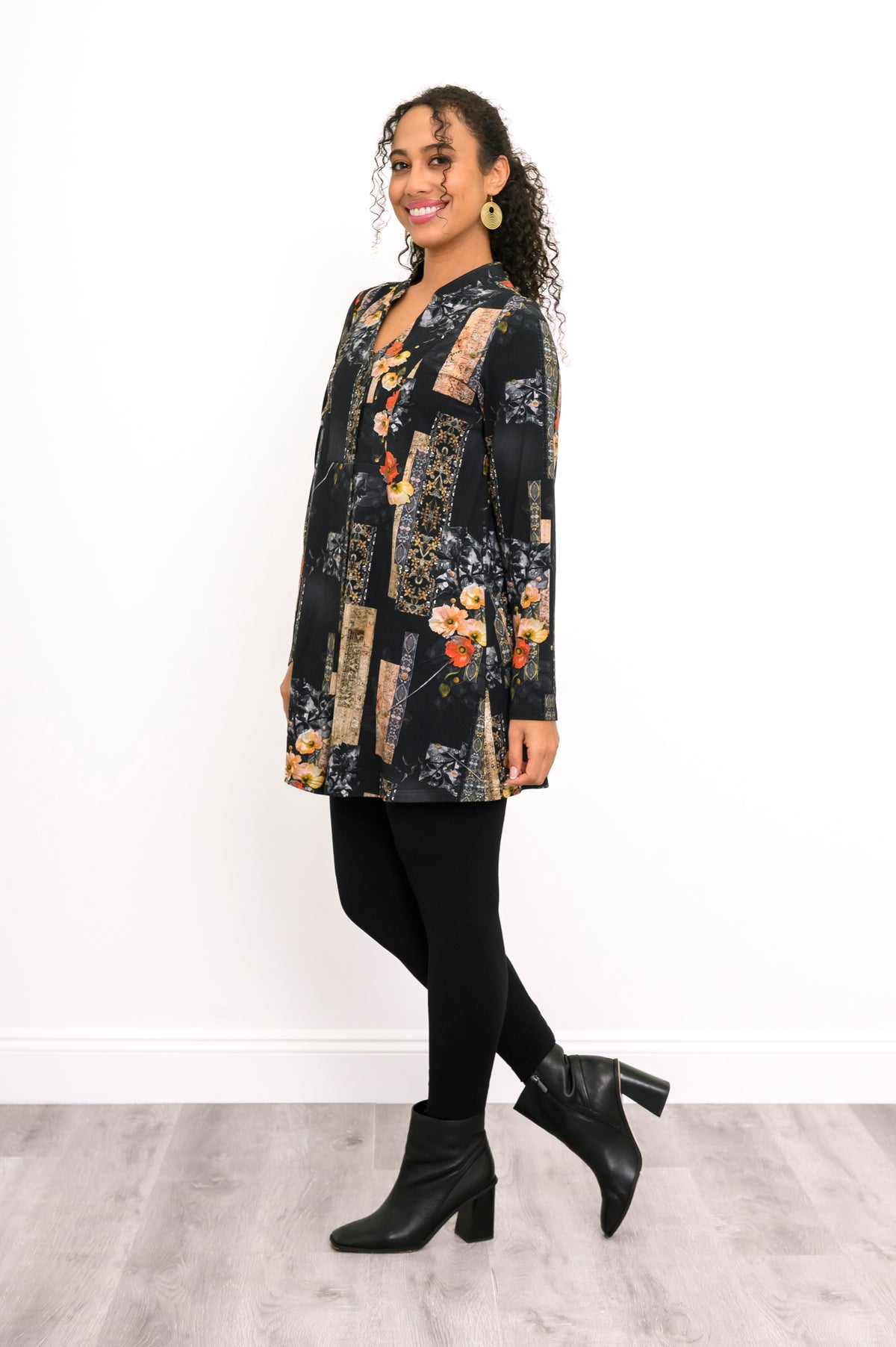 Three-quarter profile of a gold and black patterned bamboo top styled with fitted black trousers.