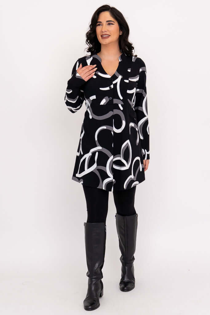Woman smiling and gesturing in Edwina tunic, black with modern white and grey design.
