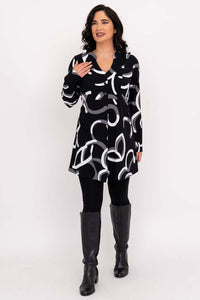 Woman smiling and gesturing in Edwina tunic, black with modern white and grey design.