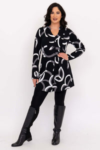 Woman standing with hand on hip in Edwina black tunic, white and grey pattern, boots.