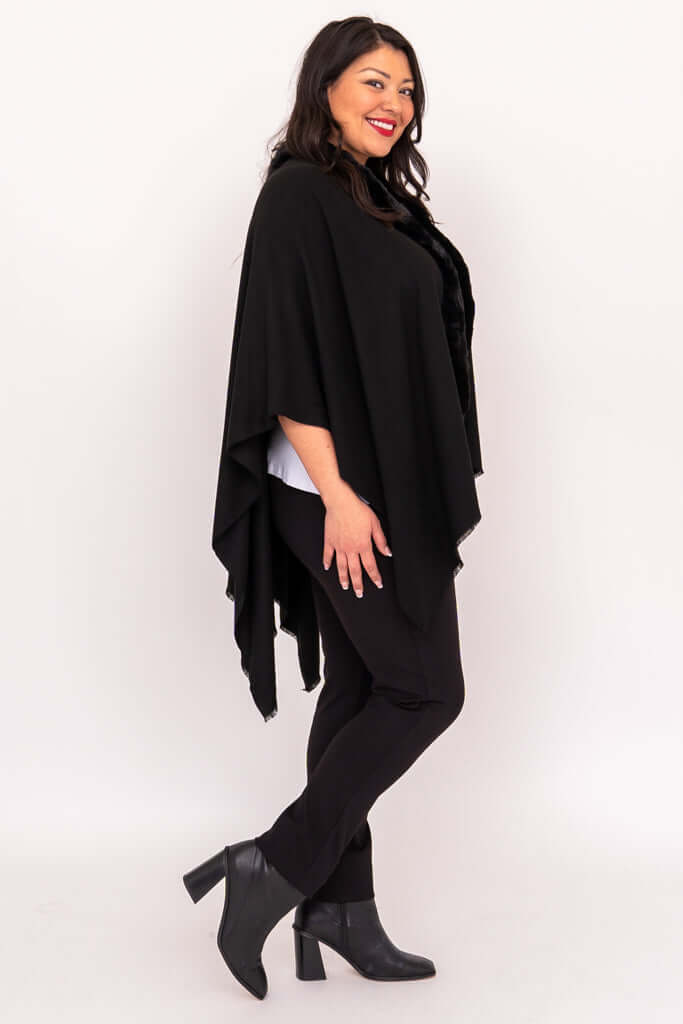 Side view of woman wearing draped black wrap with faux fur collar