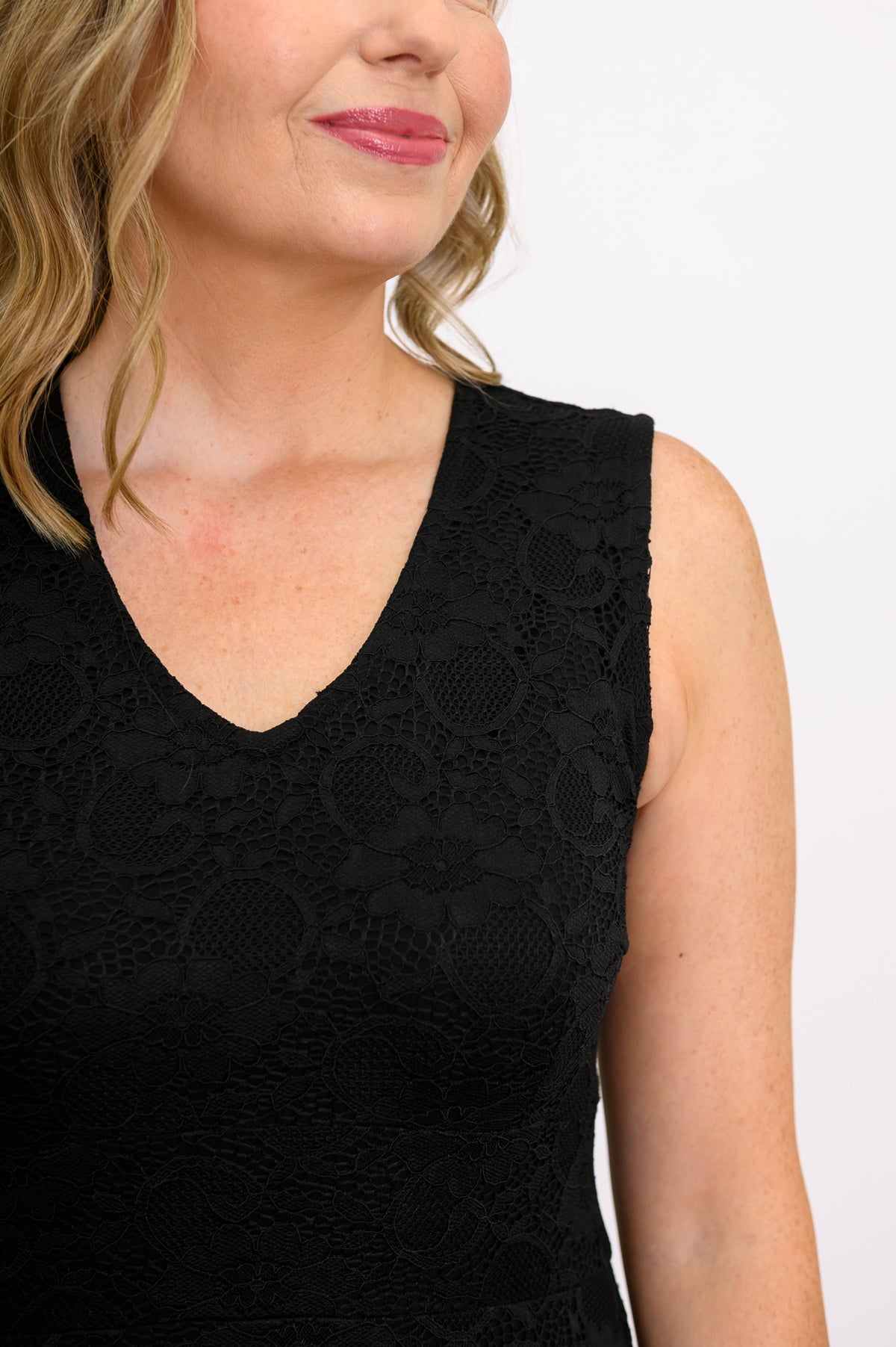 Close-up view of woman wearing sleeveless v-neck dress with black lace details