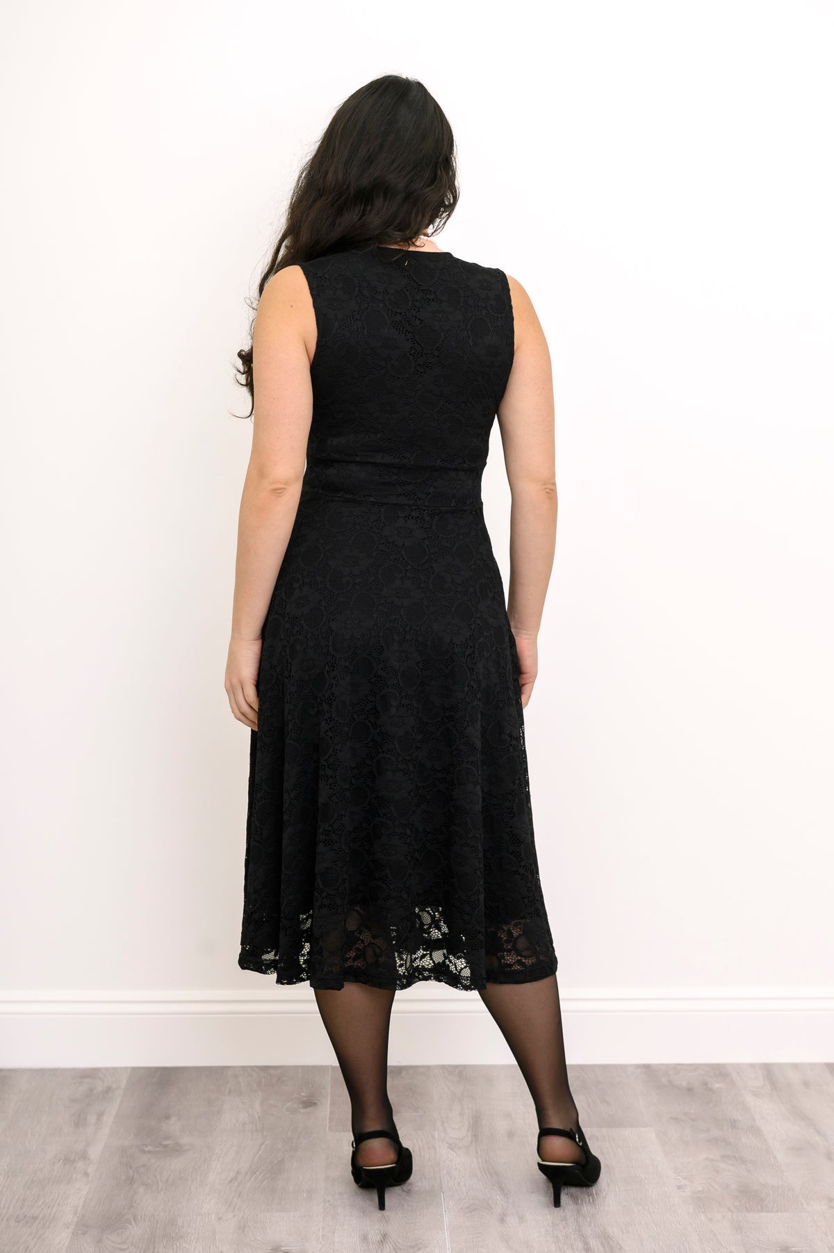 Back view of woman wearing a fit and flare dress. featuring black lace and sleeveless design