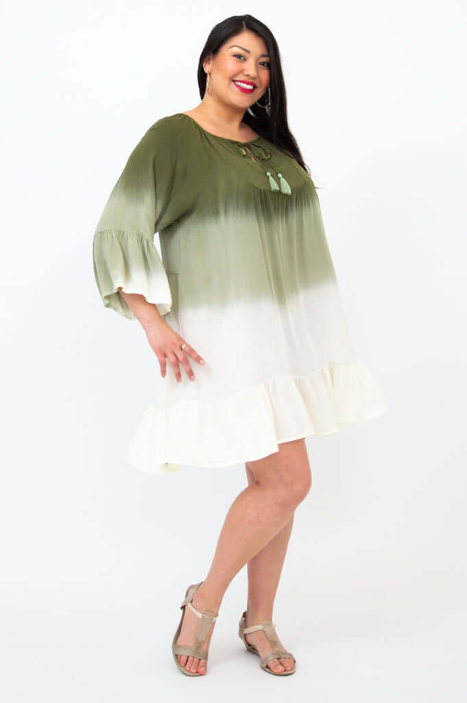 Side angle of a woman in an ombre green and white dress with ruffle details above the knee