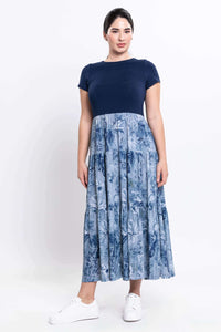 Woman standing in a navy and blue floral empire waist maxi dress with white sneakers