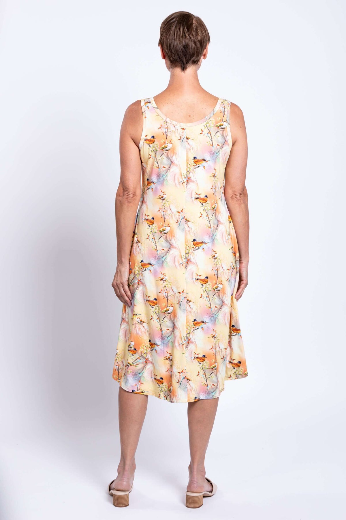 Back view of woman wearing a pastel tank dress with bird print