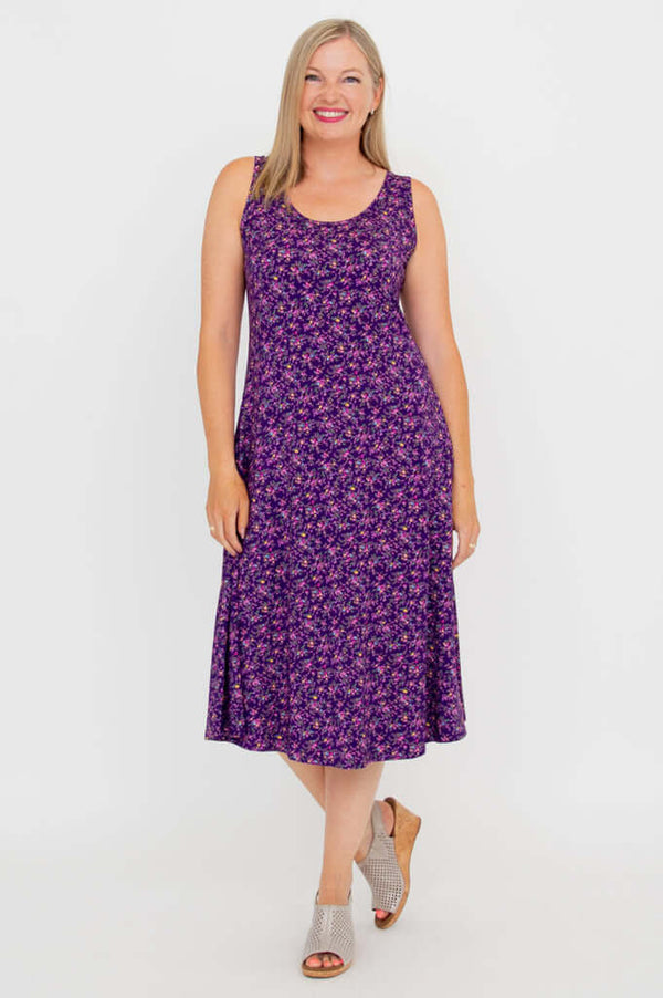 Woman posing in a purple floral sleeveless tank dress, showing the knee-length fit