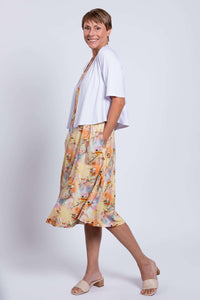 Side profile of woman in pastel bird print dress, paired with a white cardigan