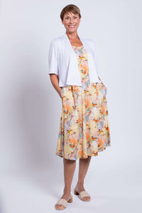 Woman in pastel tank dress with bird print, styled with a white short-sleeve cardigan