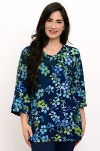 Woman wearing a blue and green floral top and navy pants against a white background, front view